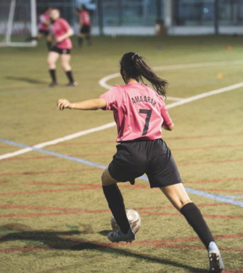 woman in red and white soccer jersey shirt and black shorts running on field during daytime
