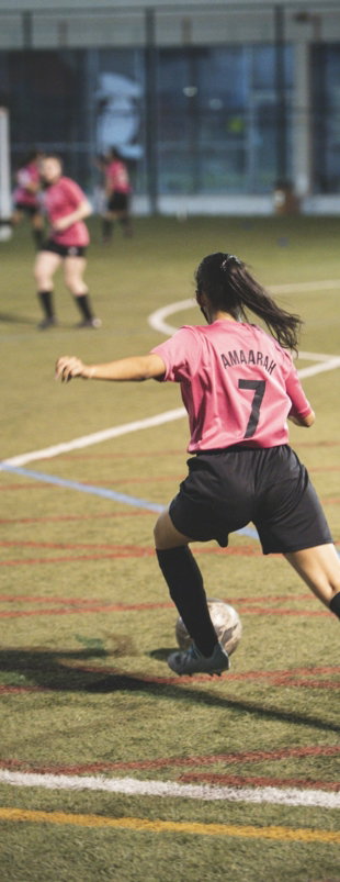 woman in red and white soccer jersey shirt and black shorts running on field during daytime